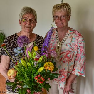2 vrouwen, waarvan 1 een bos bloemen vasthoudt